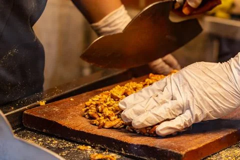 Gloved Hands Cutting Peanut Candy on Board Stock-Fotos
