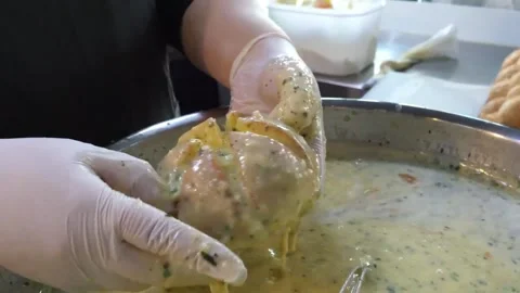 Gloved Hands Dipping Dough Ball into Thick Seasoned Batter in Stainless Steel Bo Video stock 343587502
