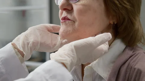 Gloved Hands of Doctor Checking Lymph Nodes of Elderly Woman at Clinic Stock Footage 333200267