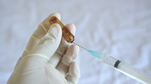 Gloved hands drawing liquid medication from an open glass ampoule Stock Footage 322205895