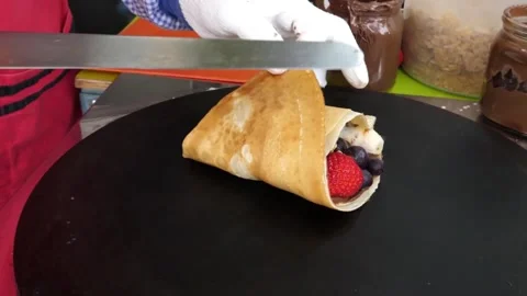Gloved Hands Folding Fresh Berry and Banana Crepe on Flat Griddle Video stock 343588191