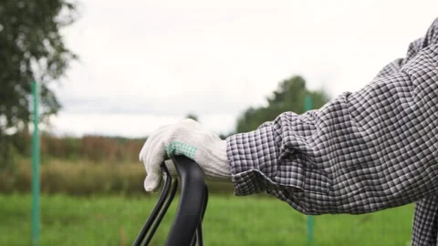 Gloved hands grasp the mowers handle in a close-up shot. Stock Footage 316800121