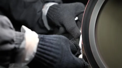 Gloved hands grinding a small metal clipper jaw on a spinning buffing wheel Vídeo Stock 345401155