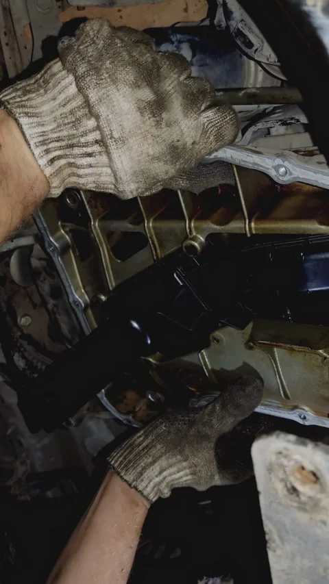 Gloved hands installing a new black plastic oil pump assembly undercar Stock Footage 336560169