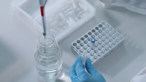 Gloved hands of a laboratory operator pour liquid into vials Stock Footage 274351187