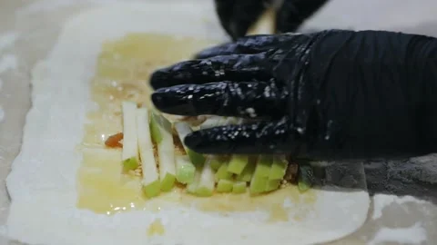 Gloved hands lay out fresh fruit for Apple strudel and bakery products on the Stock Footage 132031724