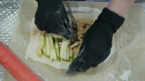 Gloved hands lay out fresh fruit for Apple strudel and bakery products on the Video stock 132031791