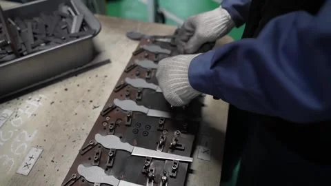 Gloved hands lay scissor half blades into the fixture slots of a long steel Stock Footage 346738112