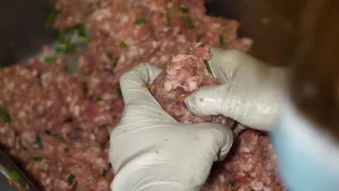 Gloved Hands Mixing Raw Minced Meat Stuffing with Herbs 動画素材 343588323