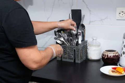 Gloved hands organizing silverware in a plastic container, setting the tabl.. Stock Photos