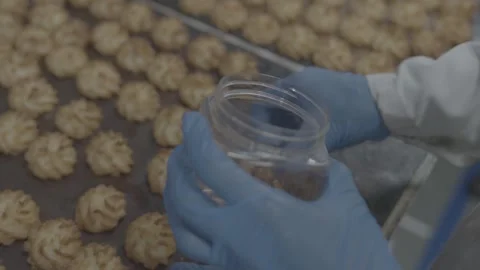 Gloved hands packing freshly baked cookies into a clear jar Stock-Footage 327357340