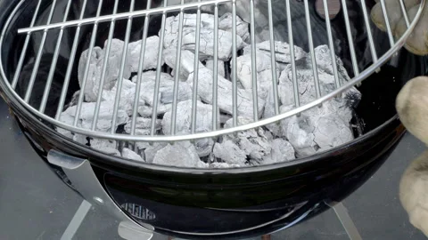 Gloved hands placing a clean grate over hot charcoal in a barbecue grill. Stock Footage 221254427