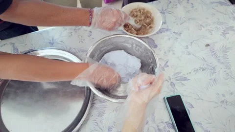 Gloved hands preparing Thai khanom tom dessert with blue dough and coconut Vídeos de archivo 310294833