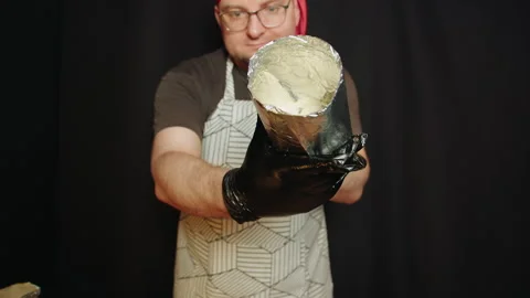 Gloved hands presenting batter container against black background Video stock 330536921