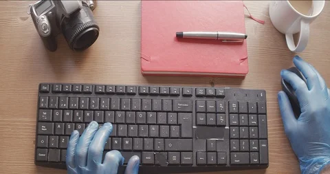 Gloved hands to protect themselves from the coronavirus by typing a computer Stock Footage 129385553