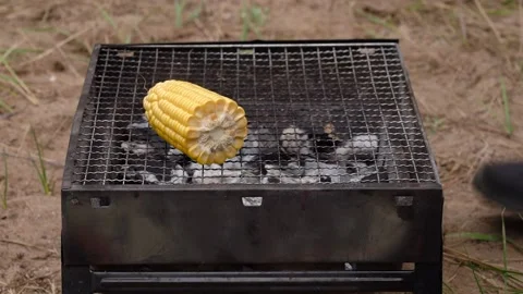 Gloved hands put a cob of corn on a barbeque grate. Stockbeeldmateriaal 161731712