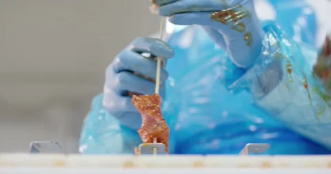 Gloved hands putting marinated meat on wooden skewers, Food Factory Stock Footage 340030796