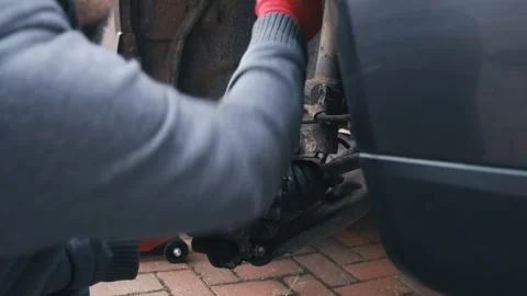 Gloved hands removing brake caliper guide pin with socket wrench during brake Stock Footage 341568833