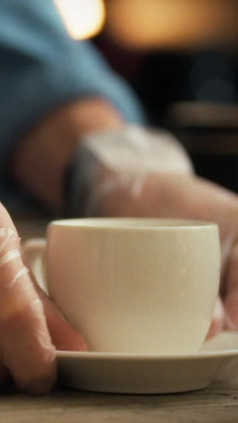 Gloved hands of a skilled barista precisely place a delicate white cup on a Stock Footage 331591366
