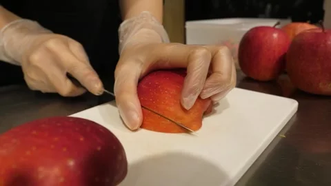 Gloved Hands Slicing Fresh Red Apple on White Cutting Board Video stock 345292894