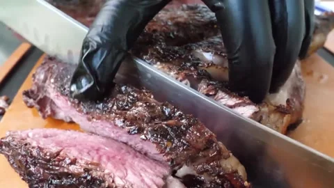 Gloved Hands Slicing Juicy Medium-Rare Barbecue Beef Steak on Cutting Board Stock Footage 338213474