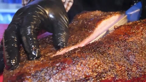 Gloved Hands Slowly Cutting Perfectly Cooked Texas Barbecue Beef Brisket on a Re Video stock 332813667