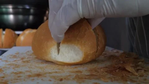 Gloved Hands Splitting Freshly Baked Crusty Bread Roll on Cutting Board 動画素材 343587458