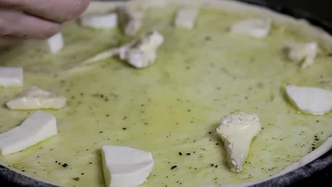 Gloved hands spread pieces of cheese on a pizza surface Stock Footage 102709117