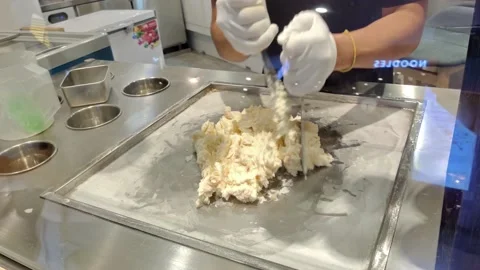 Gloved hands stir fried ice cream rolls at freeze pan. 動画素材 224000548