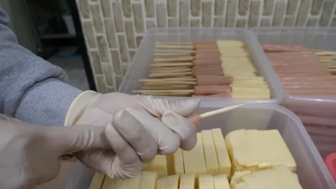 Gloved Hands Stuffing Hot Dog Casing with Cheese Blocks for Corn Dogs Video stock 343587615