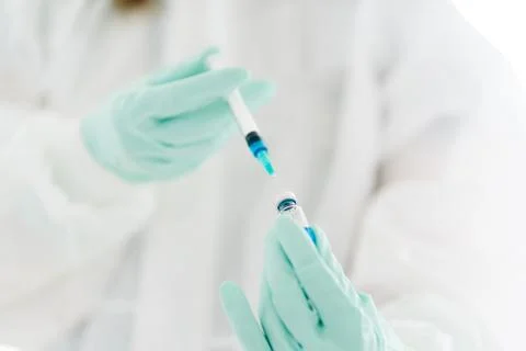 Gloved hands with a syringe and a vaccine Stock Photos