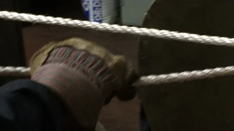 Gloved hands tightening rope around large metal object Stock Footage 123728392