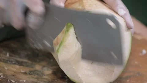Gloved Hands Trimming and Shaving a Fresh Young Green Coconut with a Large Cleav Stock Footage 345650376