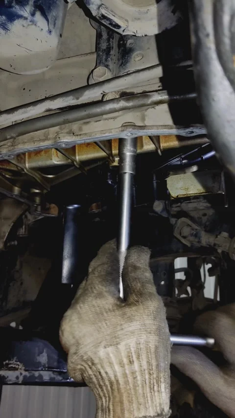 Gloved hands use socket wrench to tighten car undercarriage bolt Stock Footage 336560229
