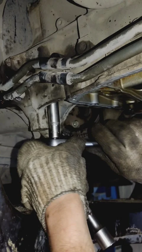 Gloved hands use socket wrench to tighten car undercarriage bolt Stock Footage 336560263