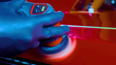Gloved hands using rotary tool to polish red car paint under uv light Stock-Footage 342905707