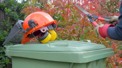 Gloved hands using shears, then putting them on green bin next to hard hat. Video stock 154732942