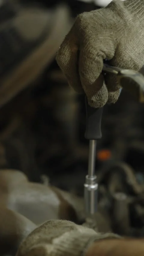 Gloved hands using a socket ratchet wrench inside car workshop Stock Footage 336711378