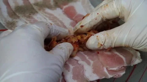 Gloved Hands Wrapping Spicy Kimchi in Slices of Raw Pork Belly Video stock 343588007