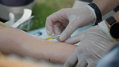 Gloved healthcare trainee inserts an IV cannula into a medical training arm Stock Footage 337690827