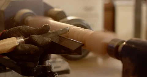 Gloved male turner lifting chisel as wood starting spinning on lathe shaping Stock Footage 310366825