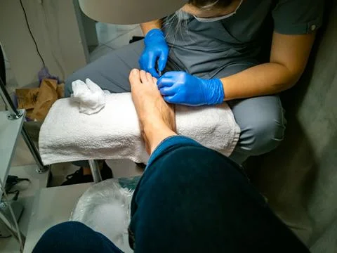 Gloved master makes a pedicure for a client. close-up no face. woman in a nail 스톡 사진