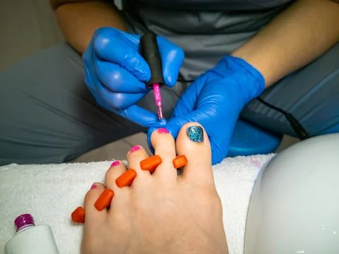 Gloved master makes a pedicure for a client. close-up no face. woman in a nail Stock Photos