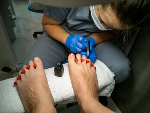 Gloved master makes a pedicure for a client. close-up no face. woman in a nail Фото