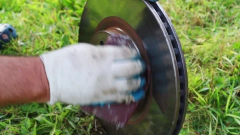 A gloved mechanic is carefully sanding the rust off the brake rotor. Full HD Vidéo 138761800