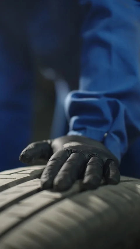 Gloved mechanic hand pressing against car tire tread during careful inspection Stock-Footage 334180563