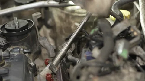A gloved mechanic using a socket wrench to bolt fuel rail into car engine. Stock Footage 342262271
