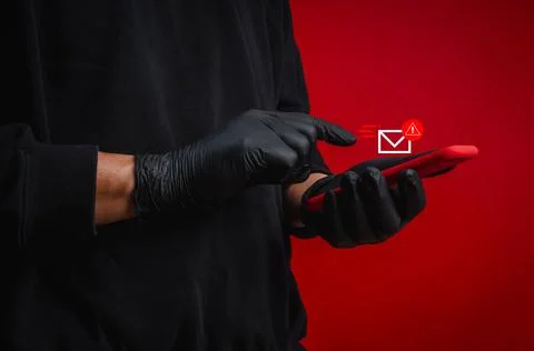 Gloved scammer hands using smartphone with suspicious message alert on red .. Stock Photos