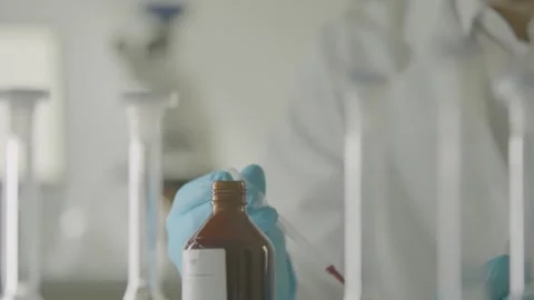 Gloved Scientist Using Pipette to Handle Liquid Sample in Laboratory Environment Stock Footage 334053132
