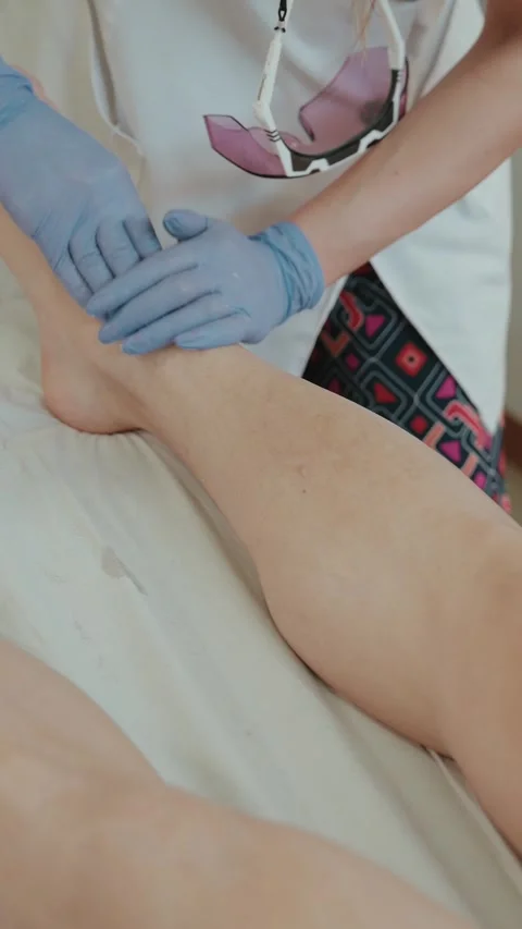 Gloved technician applying gel on client leg before laser hair removal treatment Stock Footage 333811283